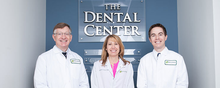 three doctors in front of practice sign